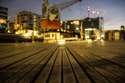 Surface level view of boardwalk against illuminated crane in city