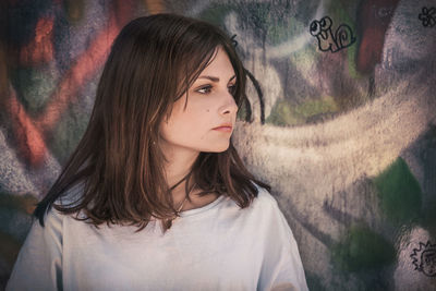 Portrait of beautiful young woman against graffiti wall