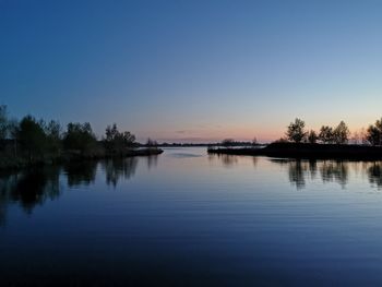 Scenic view of lake against clear sky at sunset