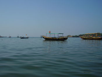 Boats sailing in sea against clear sky