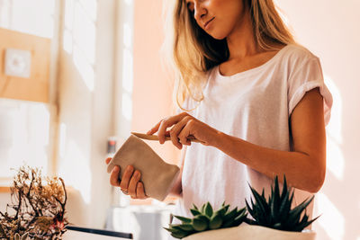 Midsection of woman holding plant at home