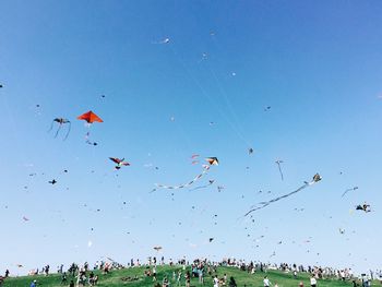 Low angle view of kites flying against blue sky