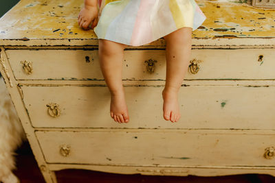 Toddler feet hanging by a vintage dresser