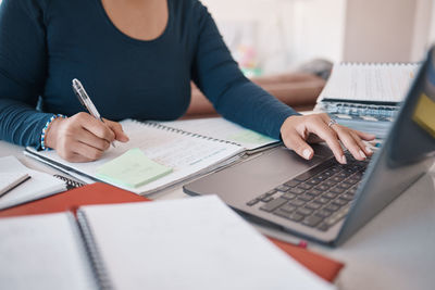 Midsection of businesswoman working at desk in office