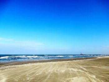 Scenic view of beach against clear blue sky
