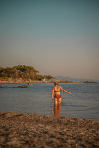 Rear view of people at beach against clear sky