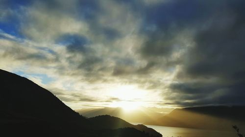 Sun shining through clouds over mountain