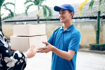 Male worker delivering packages to customer on footpath