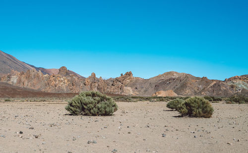 Scenic view of arid landscape against clear blue sky