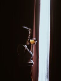 Rear view of woman standing against curtain