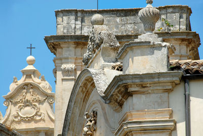 Low angle view of statues on building against sky