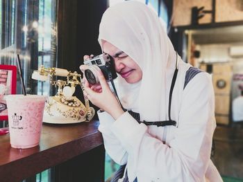 Woman photographing smoothie in cafe