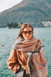 Young woman wearing sunglasses standing against mountain