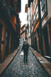 Rear view of man walking on street amidst buildings