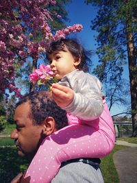 Portrait of cute girl with pink flowers against trees