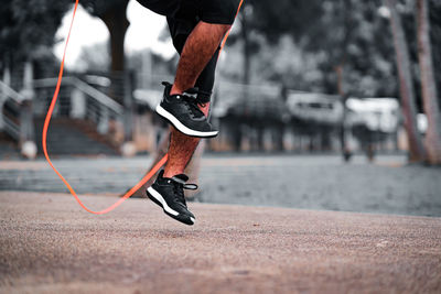 Fitness concept. healthy lifestyle. man in black jumping with skipping rope in the park.