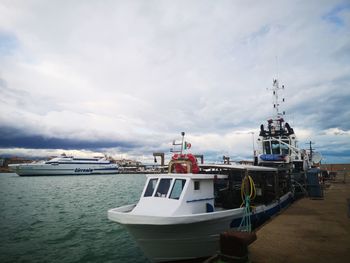 Fishing boat moored at harbor against sky