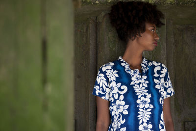 Woman looking away while standing against blue wall