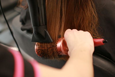 Cropped hands of hairdresser cutting woman hair