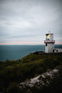 Lighthouse by sea against sky