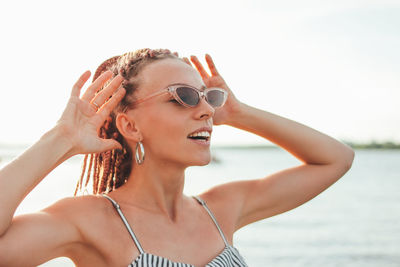 Close-up of smiling woman standing against sea