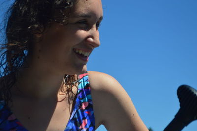 Close-up of smiling young woman against clear blue sky