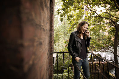 Smiling woman talking on phone while standing at fire escape