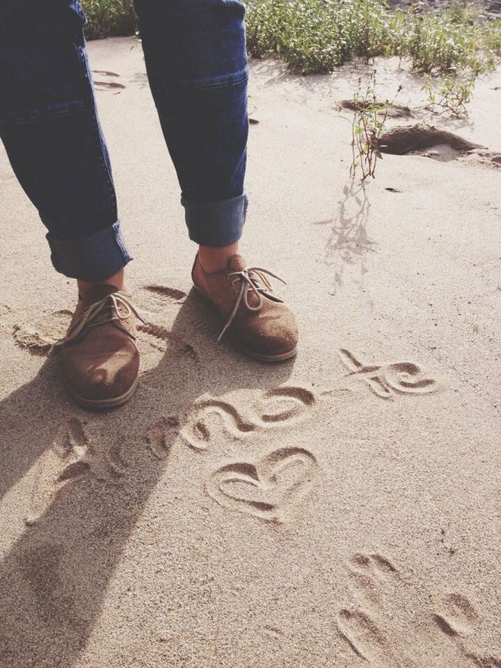 low section, person, lifestyles, sand, leisure activity, standing, beach, men, shoe, casual clothing, sunlight, jeans, outdoors, day, street, walking