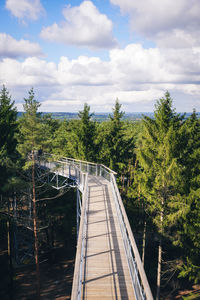 Footbridge over trees against sky