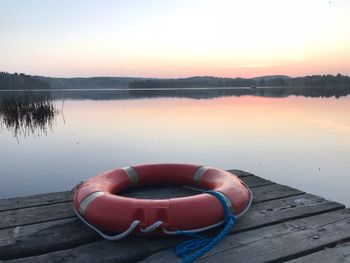 Pier on lake against sky during sunset