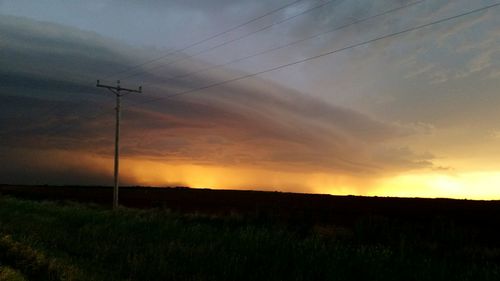 Scenic view of field against cloudy sky at sunset