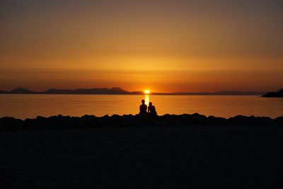 Silhouette of people in sea at sunset