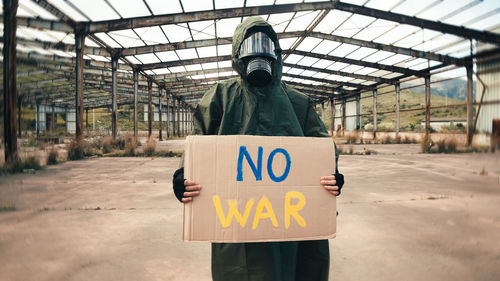 Boy with gas mask holds in hand cardboard with no war text