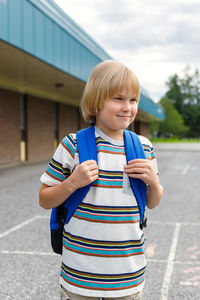 Happy smiling boy standing outdoors at schoolyard. back to school