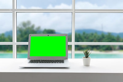 Potted plant on table by window against sky