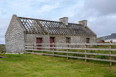 Exterior of old house on field against sky