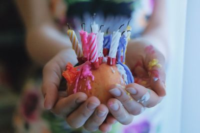 Close-up of hand holding apple with birthday candles