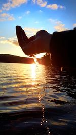 Silhouette person in sea against sky during sunset