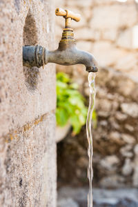 Close-up of running water from faucet on wall