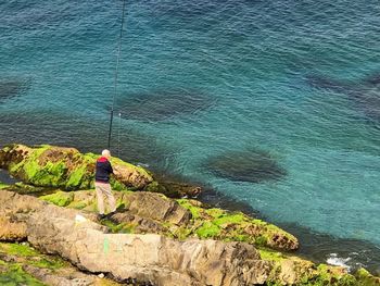 Rear view of man fishing in sea