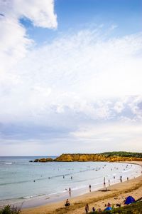 People at beach against cloudy sky