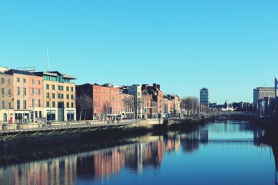 River by buildings against clear blue sky