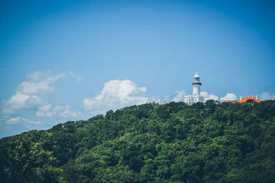 Trees and lighthouse against cloudy sky