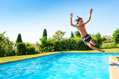 Full length of boy jumping in swimming pool