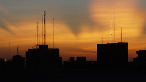 Silhouette of city against cloudy sky during sunset