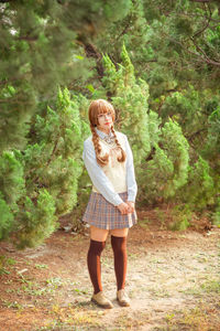 Full length portrait of woman standing in forest