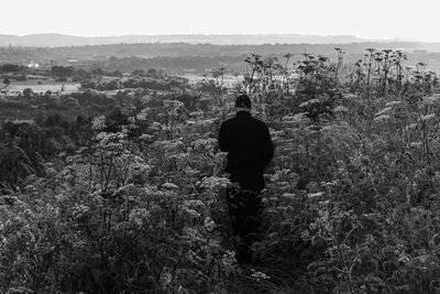 Rear view of man standing on landscape against sky