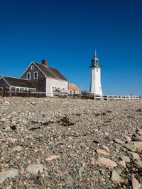 Low angle view of lighthouse by building against clear blue sky