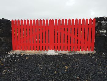 Close-up of red fence on field against sky