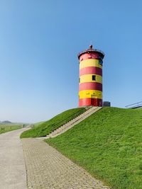 Lighthouse on field against clear sky